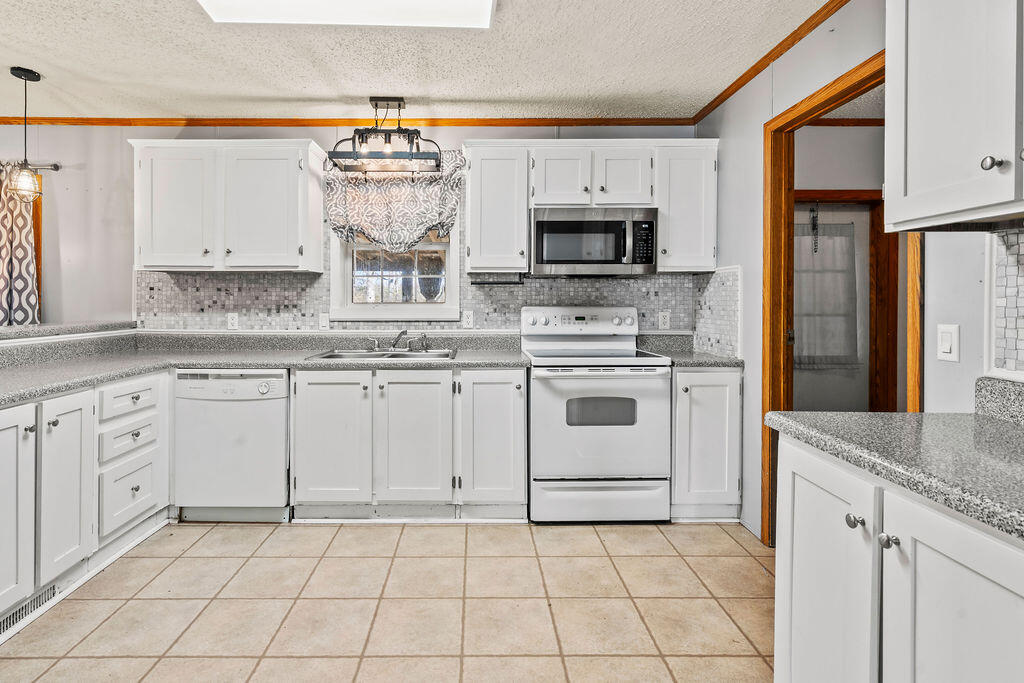 18097 Country Cross Road Florala, AL 36442 - Photo 21 of 32 a kitchen with white cabinets stainless steel appliances and sink