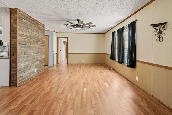 a view of empty room with wooden floor and fan