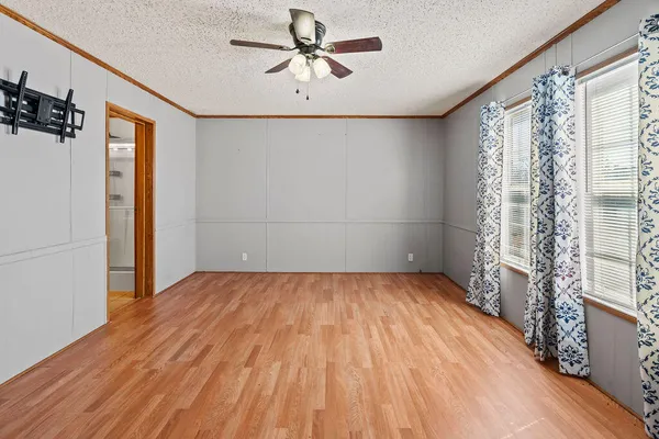 a view of empty room with wooden floor and fan