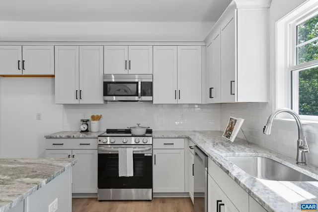 a view of a dining room and livingroom with furniture wooden floor a chandelier