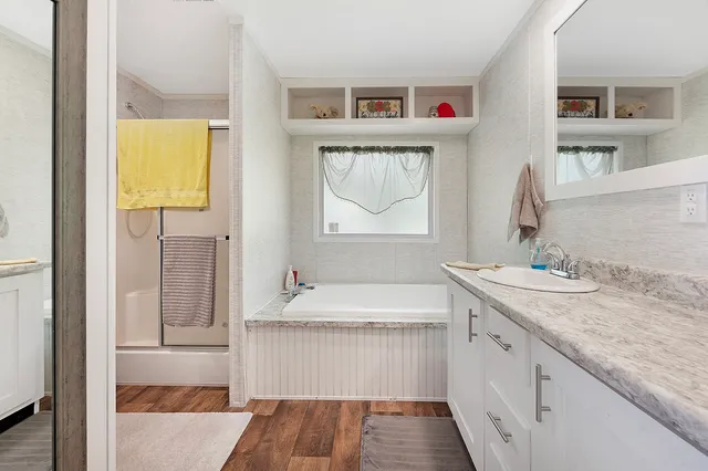 a bathroom with a granite countertop tub sink and mirror