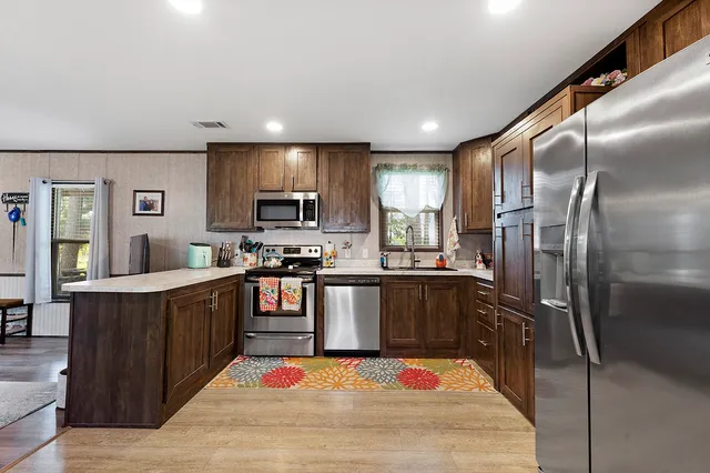 a large kitchen with stainless steel appliances kitchen island granite countertop a refrigerator and a sink