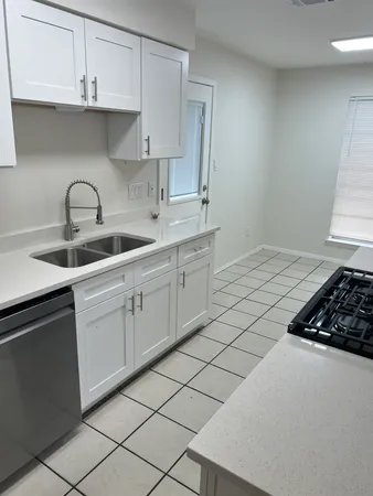 a kitchen with white cabinets a sink and dishwasher