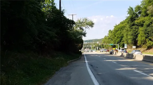 a view of a street with a bench and trees around