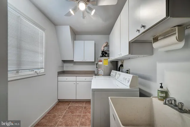 a open kitchen with stainless steel appliances granite countertop a sink dishwasher a stove a refrigerator white cabinets and couches with wooden floor