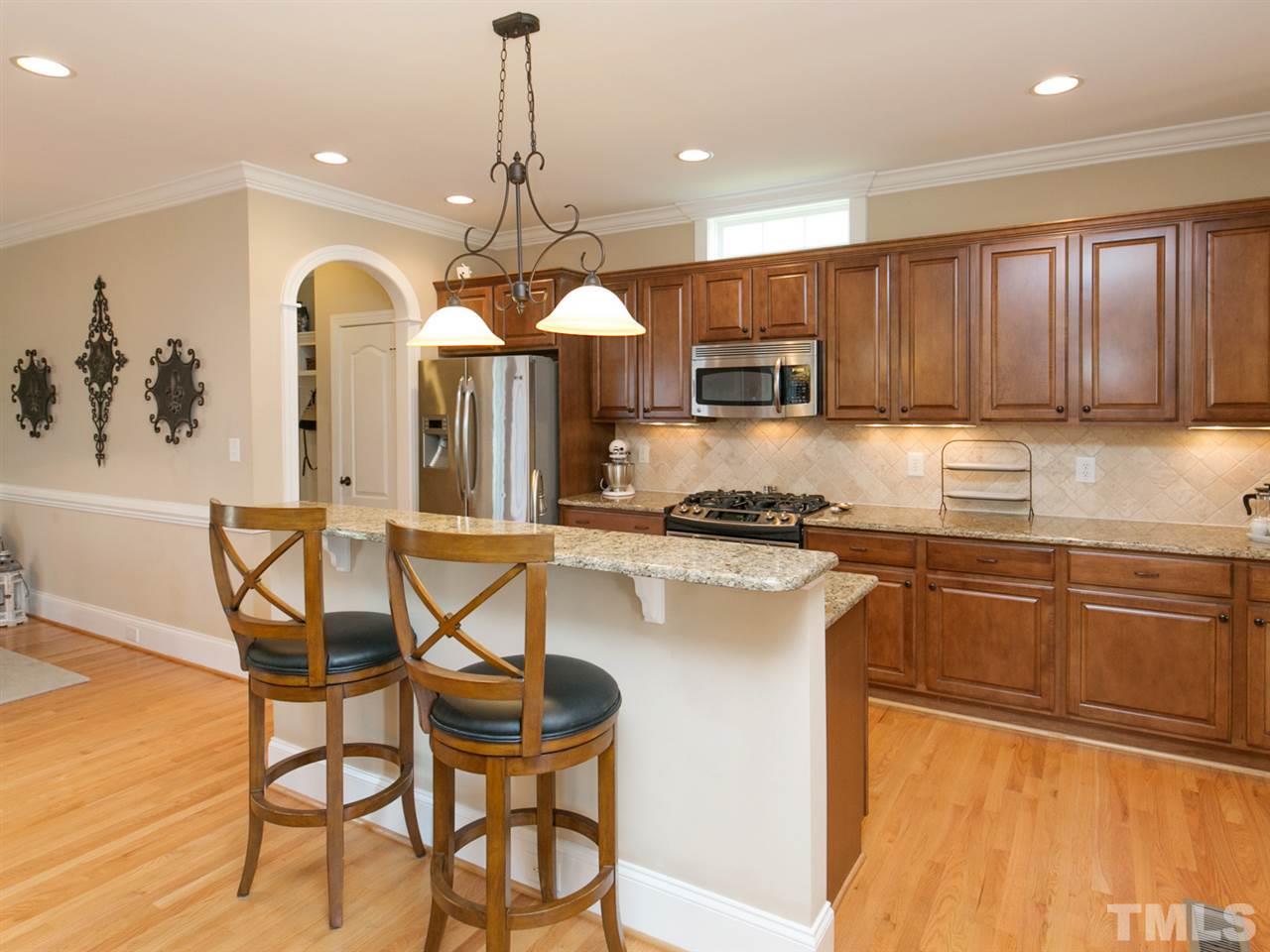 1348 Ileagnes Road Raleigh, NC 27603 - Photo 6 of 25 a kitchen with stainless steel appliances granite countertop a stove a sink dishwasher a dining table and chairs with wooden floor