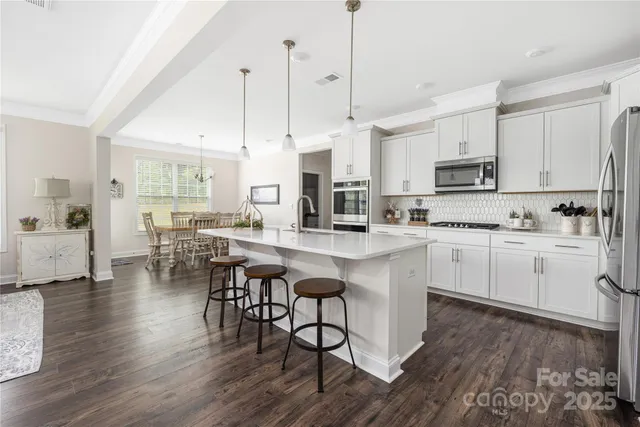 a kitchen with stainless steel appliances kitchen island granite countertop a stove a sink a center island and cabinets