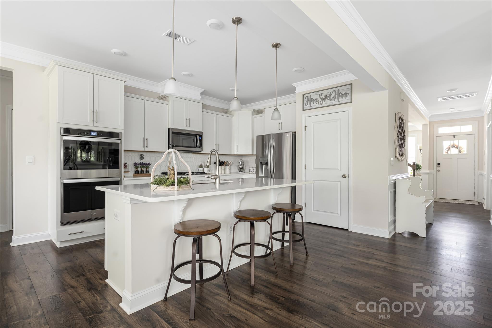 121 Rhuidean Court Troutman, NC 28166 - Photo 20 of 44 a kitchen with stainless steel appliances granite countertop a refrigerator a stove top oven a sink dishwasher and white cabinets with wooden floor
