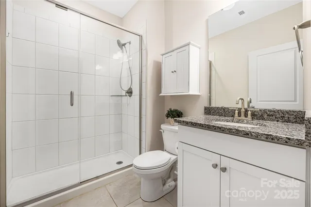 a bathroom with a granite countertop sink a toilet and shower