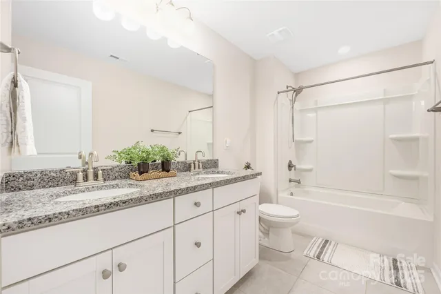 a bathroom with a granite countertop sink mirror vanity and toilet