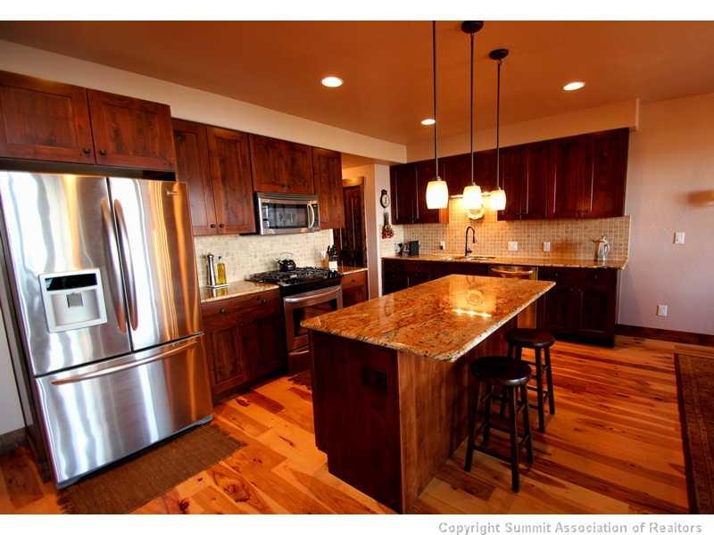 75 Uncle Sam Lode Road Breckenridge, CO 80424 - Photo 3 of 16 a kitchen with stainless steel appliances kitchen island granite countertop a refrigerator a sink dishwasher a stove and a dining table with wooden cabinet