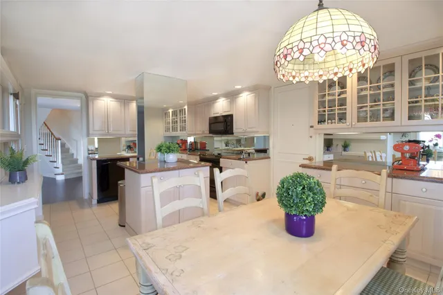 a kitchen with stainless steel appliances kitchen island granite countertop a refrigerator a stove a sink dishwasher and white cabinets with wooden floor