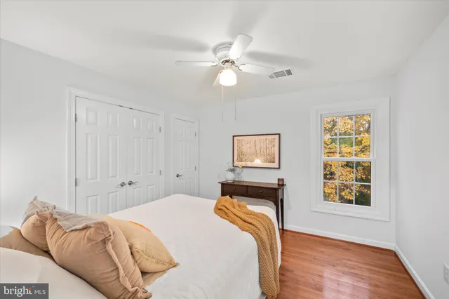 a view of an empty room with chandelier fan and wooden floor