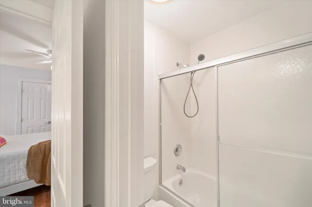 a view of empty room with wooden floor and fan