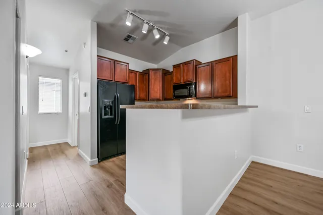 a kitchen with stainless steel appliances granite countertop a refrigerator a sink dishwasher a stove and white countertops with wooden floor