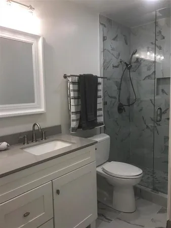 a bathroom with a granite countertop toilet sink and shower