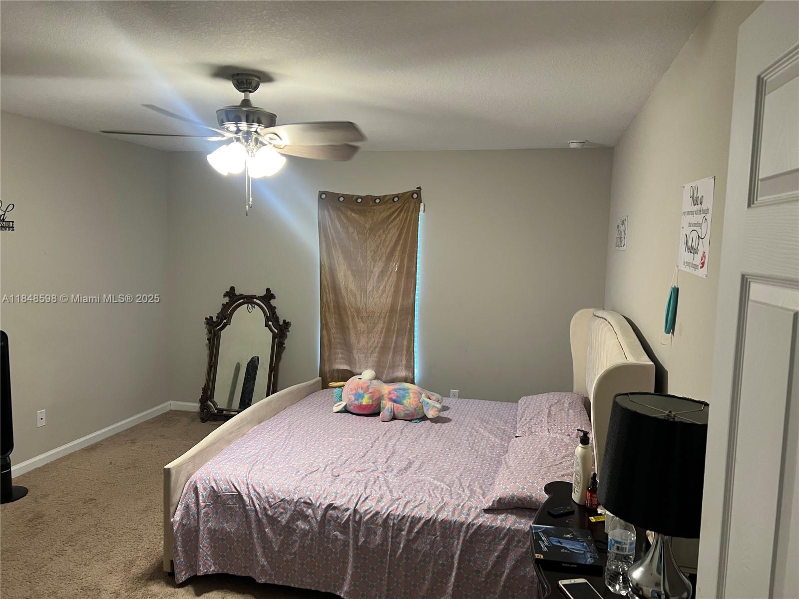 172 Southwest Langfield Avenue Port St. Lucie, FL 34984 - Photo 12 of 24 a bedroom with a bed and a chandelier