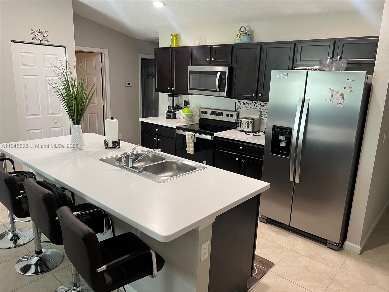 172 Southwest Langfield Avenue Port St. Lucie, FL 34984 - Photo 4 of 24 a kitchen with a refrigerator a sink a kitchen island and a refrigerator