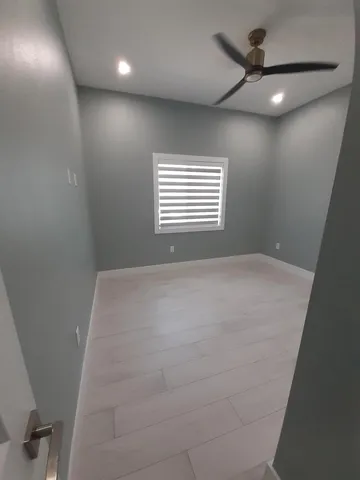 an empty room with a ceiling fan and window