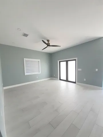 an empty room with windows and ceiling fan