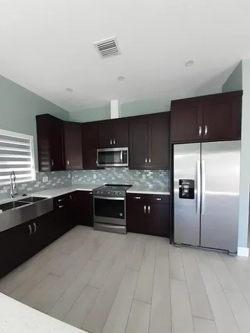 a large kitchen with a large counter top stainless steel appliances and cabinets