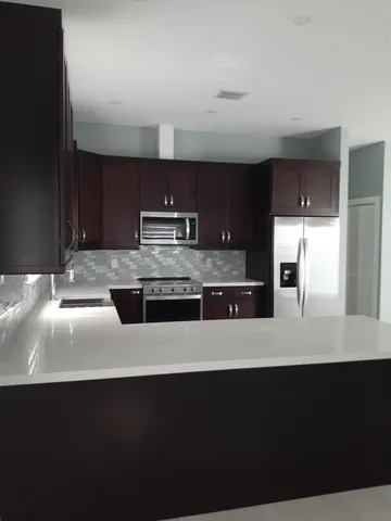 a large kitchen with granite countertop a stove a sink and a refrigerator