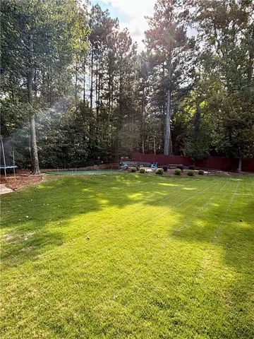 a view of a large pool with lawn chairs under an umbrella