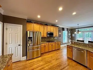 a large kitchen with stainless steel appliances granite countertop a refrigerator and a stove top oven
