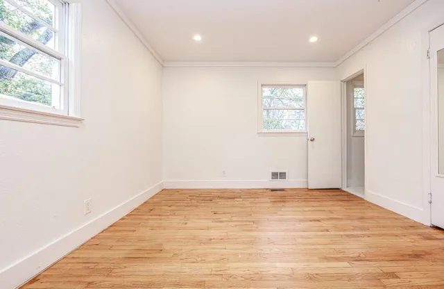 a view of empty room with wooden floor and fan
