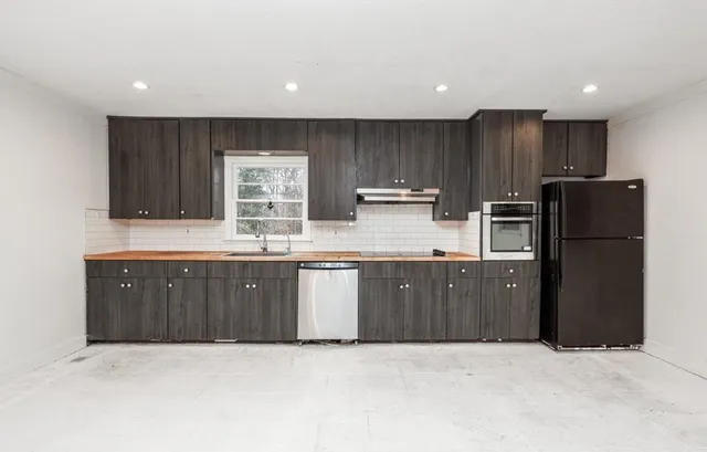 a kitchen with granite countertop stainless steel appliances a refrigerator and wooden cabinets