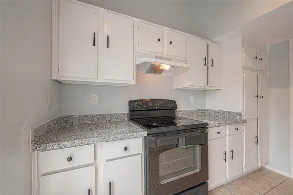 a kitchen with granite countertop a sink stove and cabinets