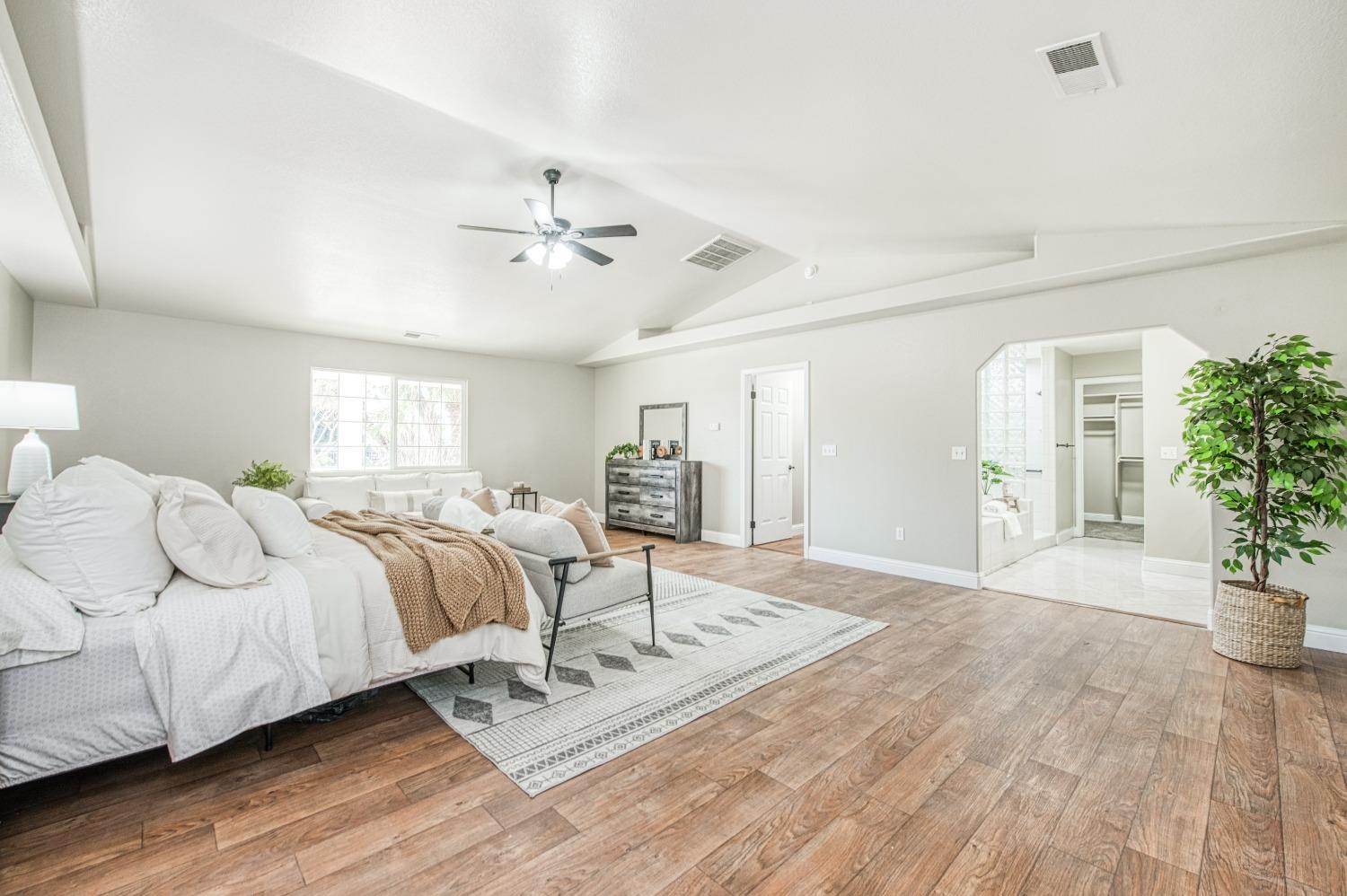 24607 Gardena Drive Madera, CA 93638 - Photo 24 of 74 a spacious bedroom with a bed a couch and potted plant