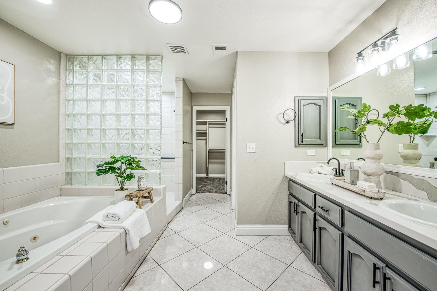 24607 Gardena Drive Madera, CA 93638 - Photo 25 of 74 a spacious bathroom with a double vanity sink a large mirror and a bathtub