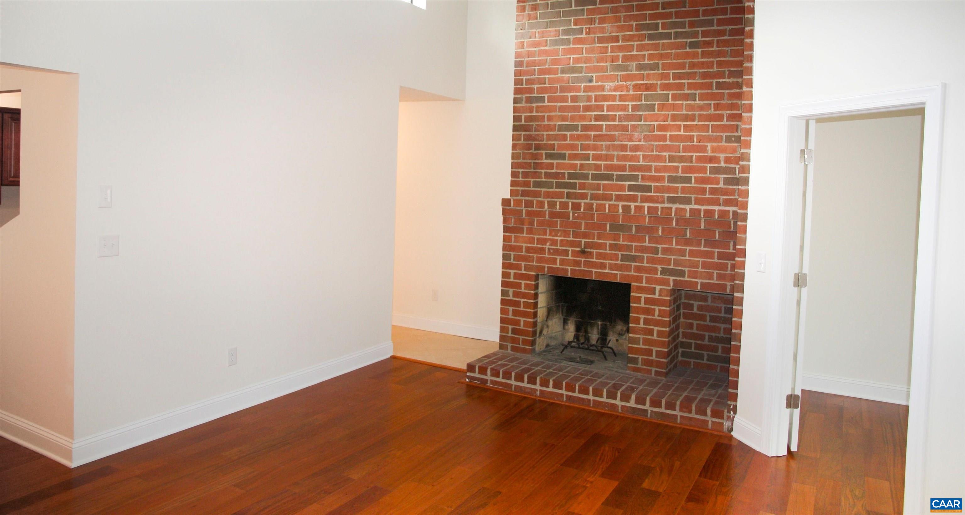 a view of a livingroom with wooden floor and a fireplace