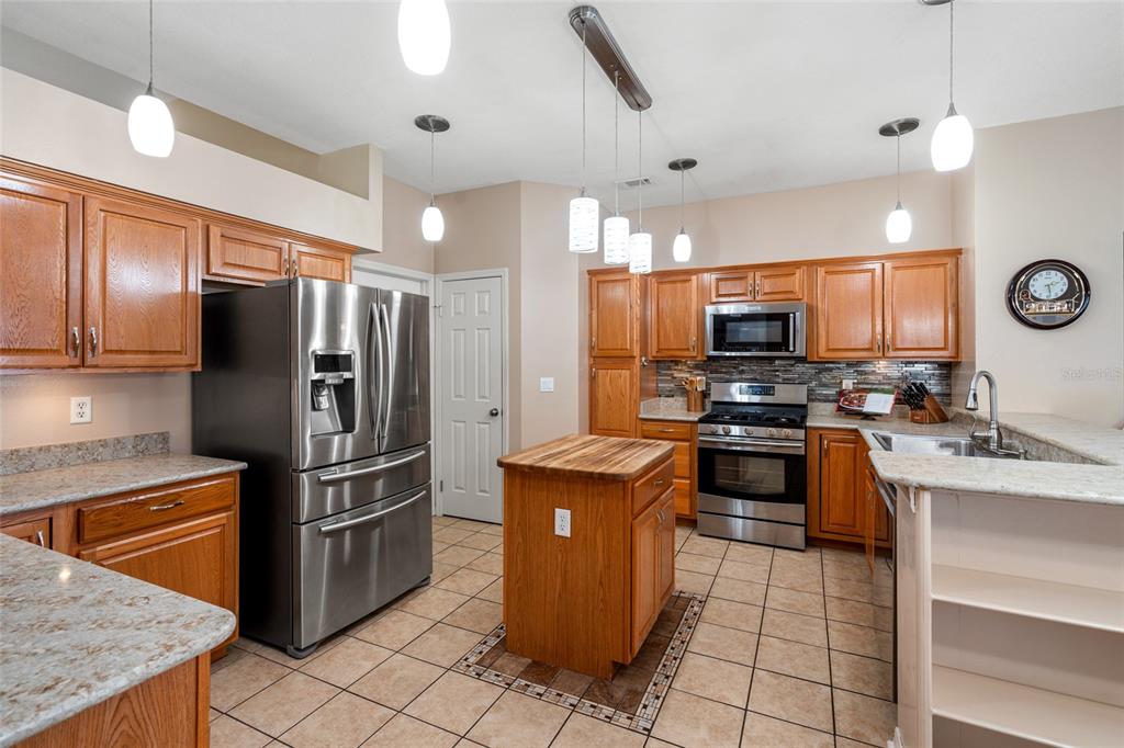 28390 Openfield Loop Wesley Chapel, FL 33543 - Photo 11 of 44 a kitchen with granite countertop a refrigerator and a stove