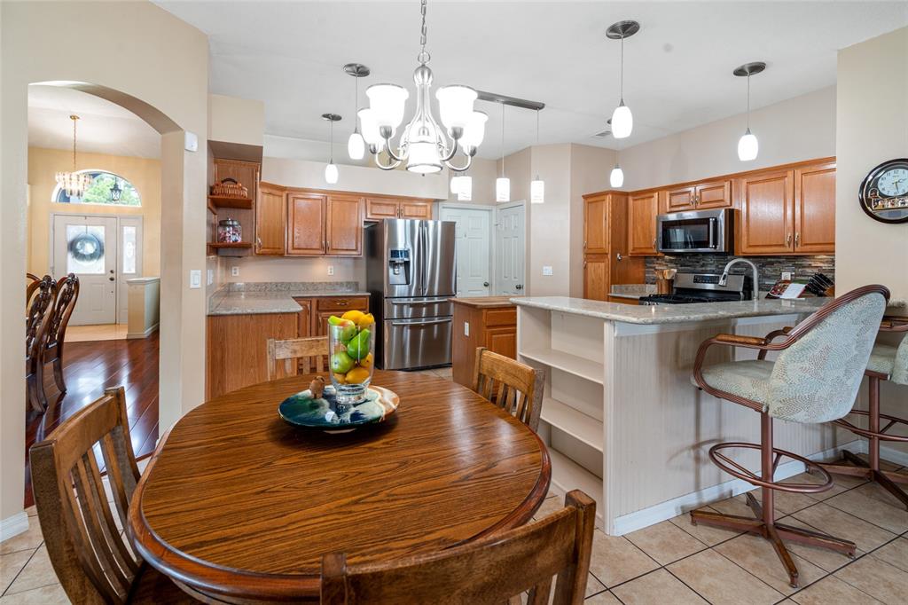 28390 Openfield Loop Wesley Chapel, FL 33543 - Photo 14 of 44 a room with stainless steel appliances kitchen island granite countertop a table chairs and a chandelier