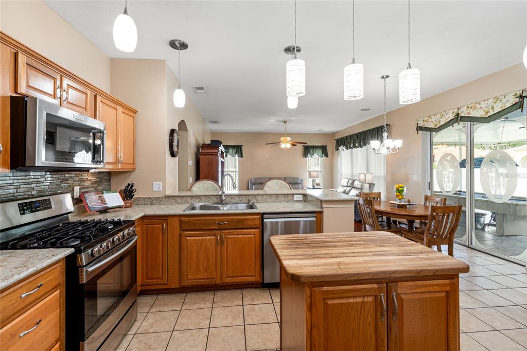28390 Openfield Loop Wesley Chapel, FL 33543 - Photo 16 of 44 a kitchen with a stove a sink a dining table and chairs
