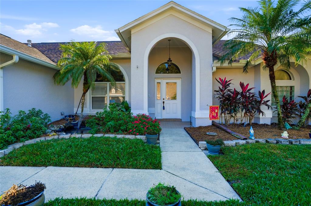 28390 Openfield Loop Wesley Chapel, FL 33543 - Photo 2 of 44 a front view of yellow house with a yard and potted plants
