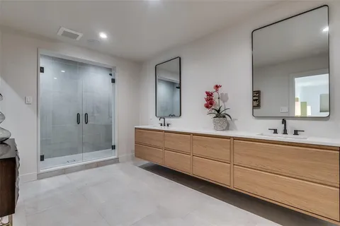 a bathroom with a double vanity sink mirror and shower