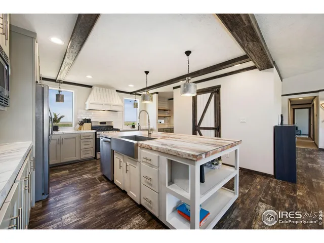 a kitchen with stainless steel appliances kitchen island granite countertop a refrigerator a stove top oven a sink dishwasher and wooden cabinets with wooden floor