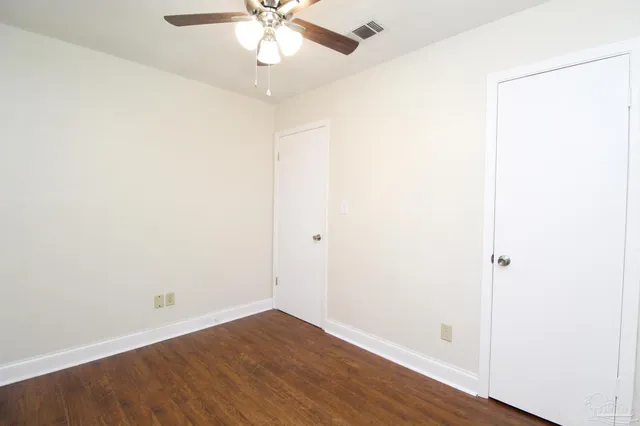 an empty room with wooden floor and fan