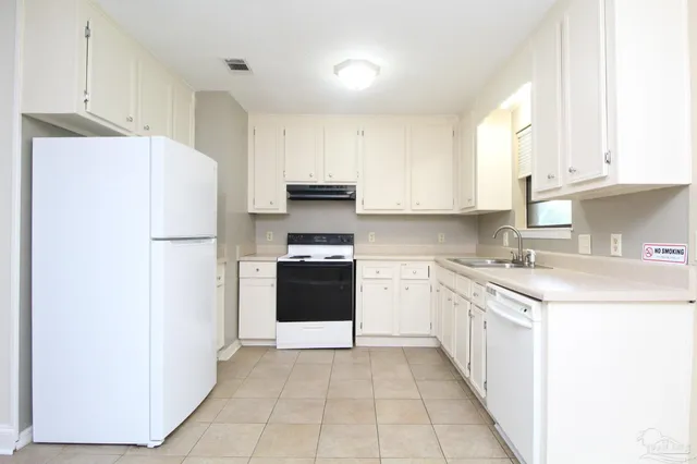 a kitchen with granite countertop a refrigerator stove top oven and cabinets