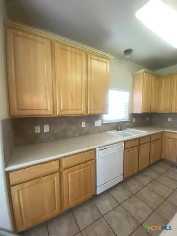 a kitchen with cabinets appliances a sink and a window