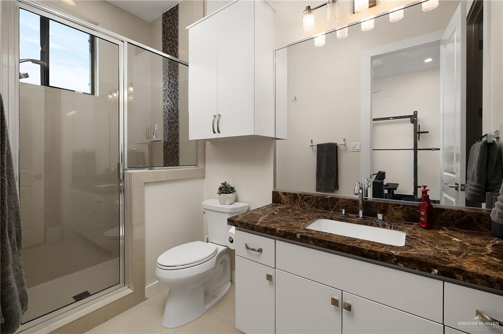 4401 South L Street McAllen, TX 78503 - Photo 16 of 20 a bathroom with a granite countertop sink toilet a mirror and shower