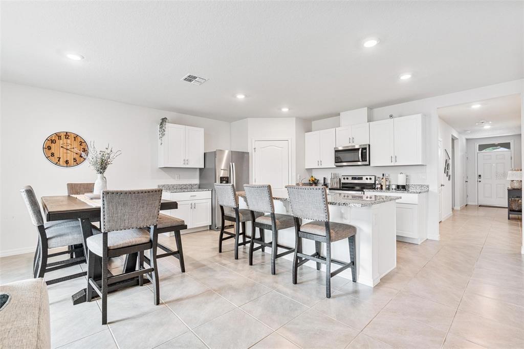 511 Baroness Way DeLand, FL 32724 - Photo 8 of 37 a kitchen with a dining table chairs refrigerator and cabinets