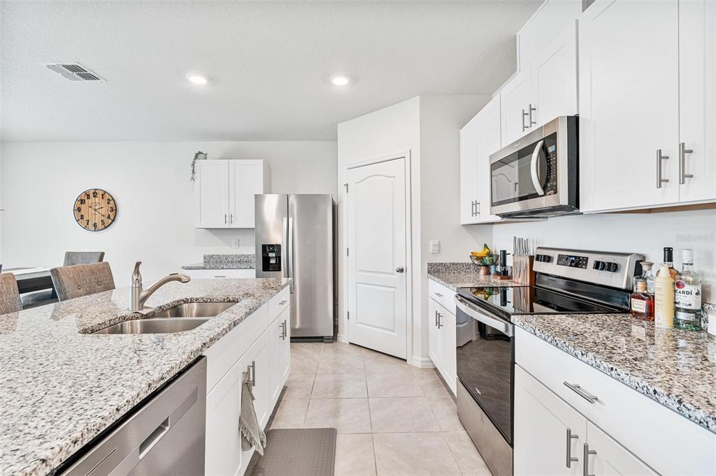 511 Baroness Way DeLand, FL 32724 - Photo 10 of 37 a kitchen with stainless steel appliances granite countertop a sink dishwasher stove and refrigerator