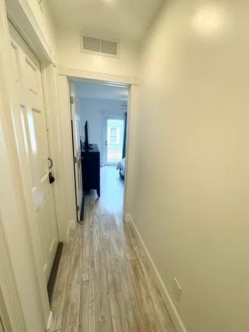 a view of a hallway with wooden floor and a bathroom