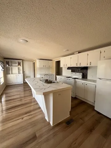 a large white kitchen with cabinets a sink and a stove