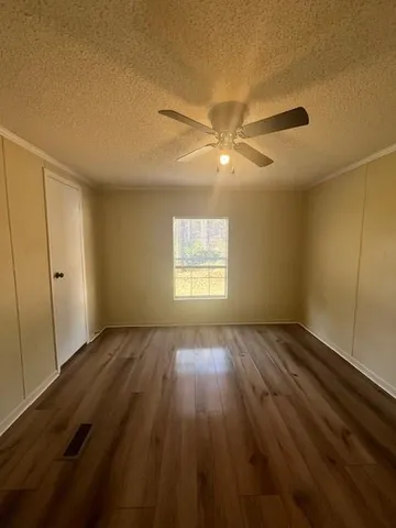 an empty room with wooden floor fan and windows