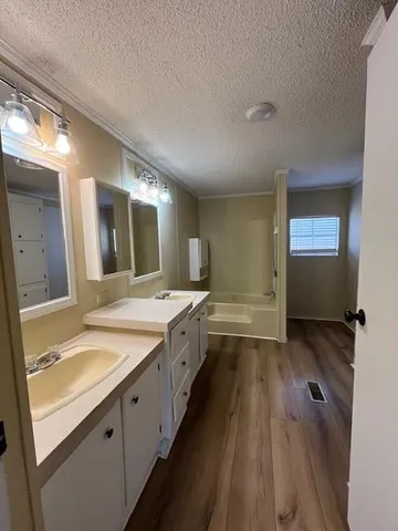 a spacious bathroom with a granite countertop sink mirror and a bathtub